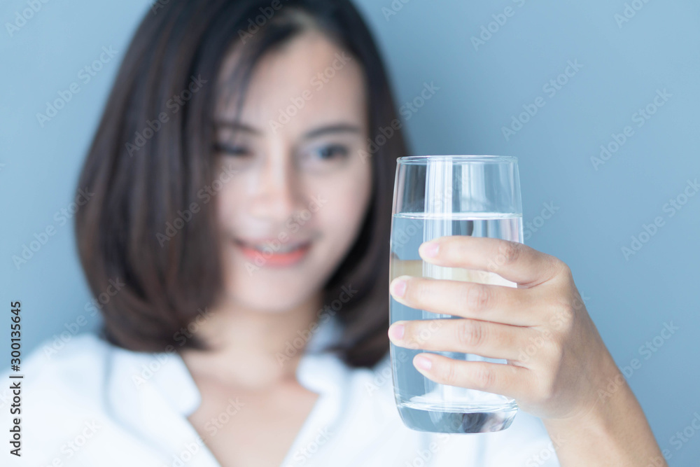 Close up woman hand holding glass of pure water with smile face background, Selective focus Close up woman hand holding glass of pure water with smile face background, Selective focus