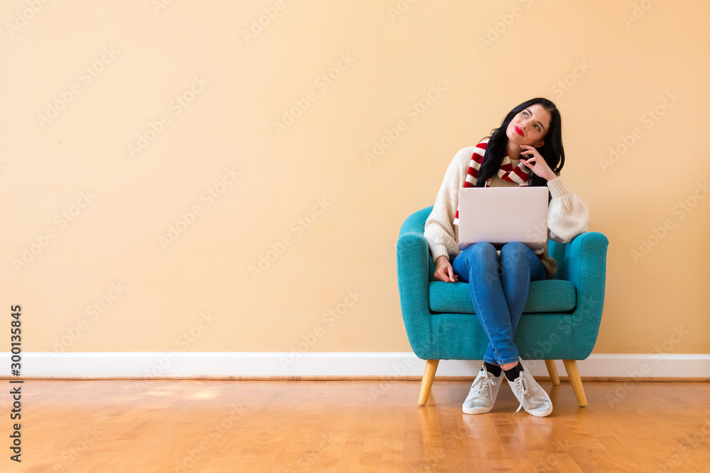 Young woman with a laptop computer in a thoughtful pose sitting in a chair Young woman with a laptop computer in a thoughtful pose sitting in a chair