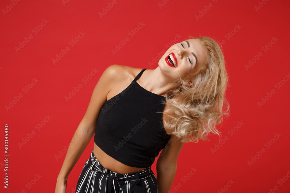 Laughing beautiful young woman girl in black clothes posing isolated on bright red wall background, studio portrait. People sincere emotions lifestyle concept. Mock up copy space. Keeping eyes closed. Laughing beautiful young woman girl in black clothes posing isolated on bright red wall background, studio portrait. People sincere emotions lifestyle concept. Mock up copy space. Keeping eyes closed.