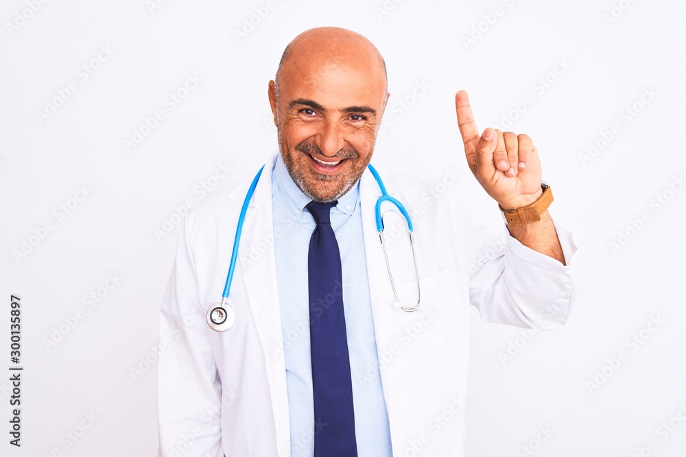 Middle age doctor man wearing stethoscope and tie standing over isolated white background showing and pointing up with finger number one while smiling confident and happy. Middle age doctor man wearing stethoscope and tie standing over isolated white background showing and pointing up with finger number one while smiling confident and happy.