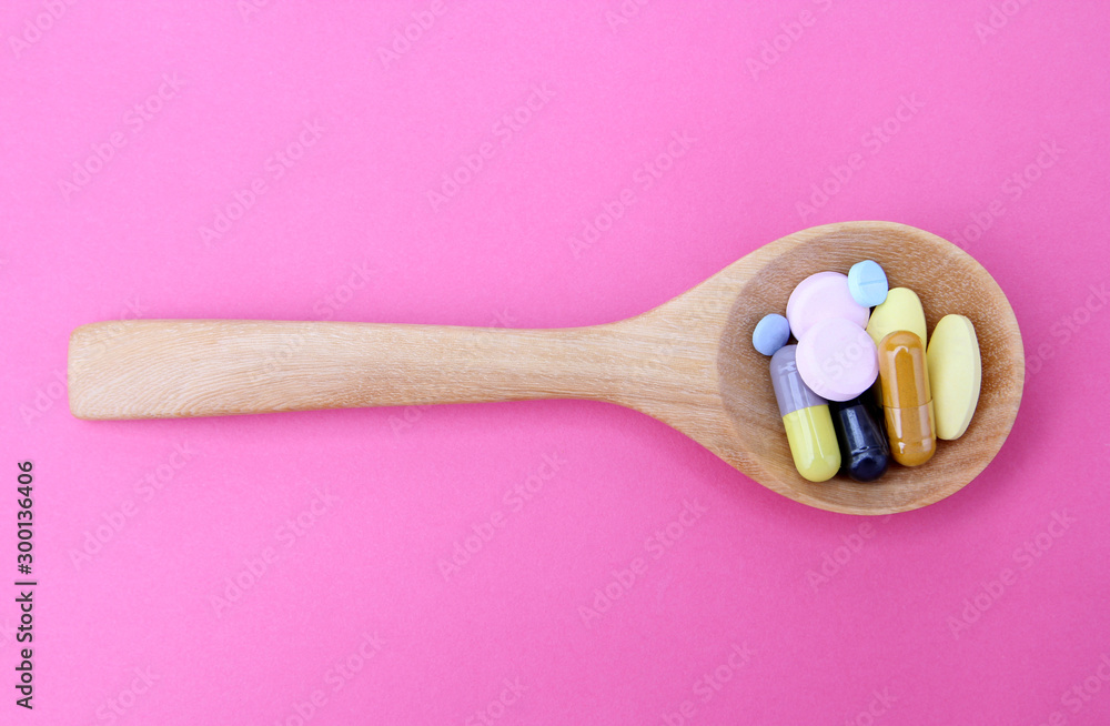 Medicine in wooden spoon isolated on a pink background. Medicine in wooden spoon isolated on a pink background.