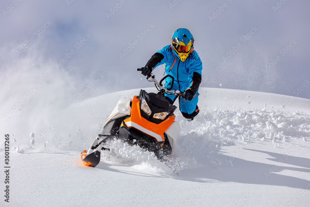 the guy turns a snowmobile in a mountain valley on the background of the clear snow and sky, leaving behind a trail of splashes. bright snow bike and suit without brands. Boondocker sports snowmobile the guy turns a snowmobile in a mountain valley on the background of the clear snow and sky, leaving behind a trail of splashes. bright snow bike and suit without brands. Boondocker sports snowmobile