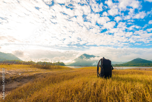 Black backpack on the yellow grass background with mountain view photo