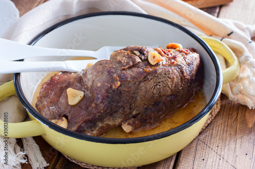 Baked beef fillet with pieces of garlic in a pan, horizontal