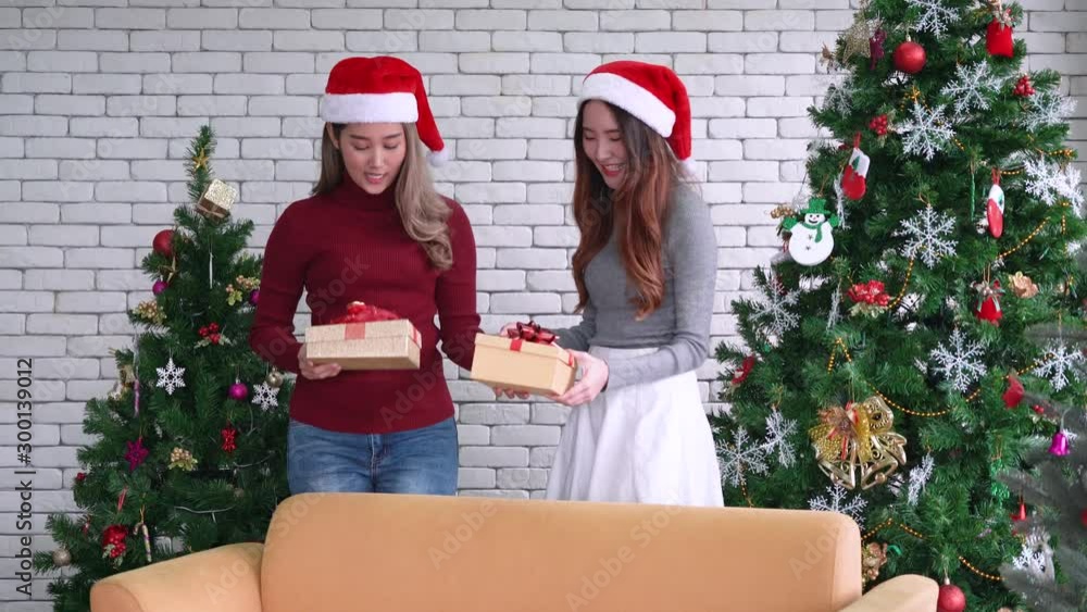 Asian women exchange gift then opening gift box and embrace together in Christmas party Asian women exchange gift then opening gift box and embrace together in Christmas party