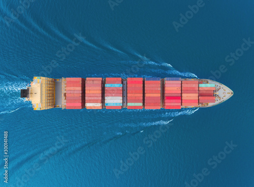 Aerial top view container cargo ship full speed with beautiful wave pattern for business logistics, import export, shipping or transportation.