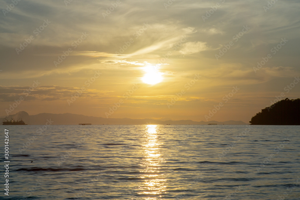 Landscape of sea with silhouette of island and orange light of sunrise