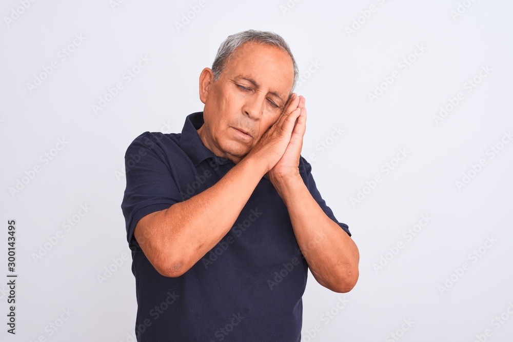 Senior grey-haired man wearing black casual polo standing over isolated white background sleeping tired dreaming and posing with hands together while smiling with closed eyes. Senior grey-haired man wearing black casual polo standing over isolated white background sleeping tired dreaming and posing with hands together while smiling with closed eyes.