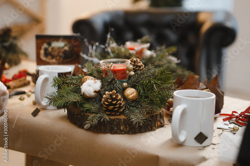 making Christmas decorations from red candles, Christmas tree branches and cones