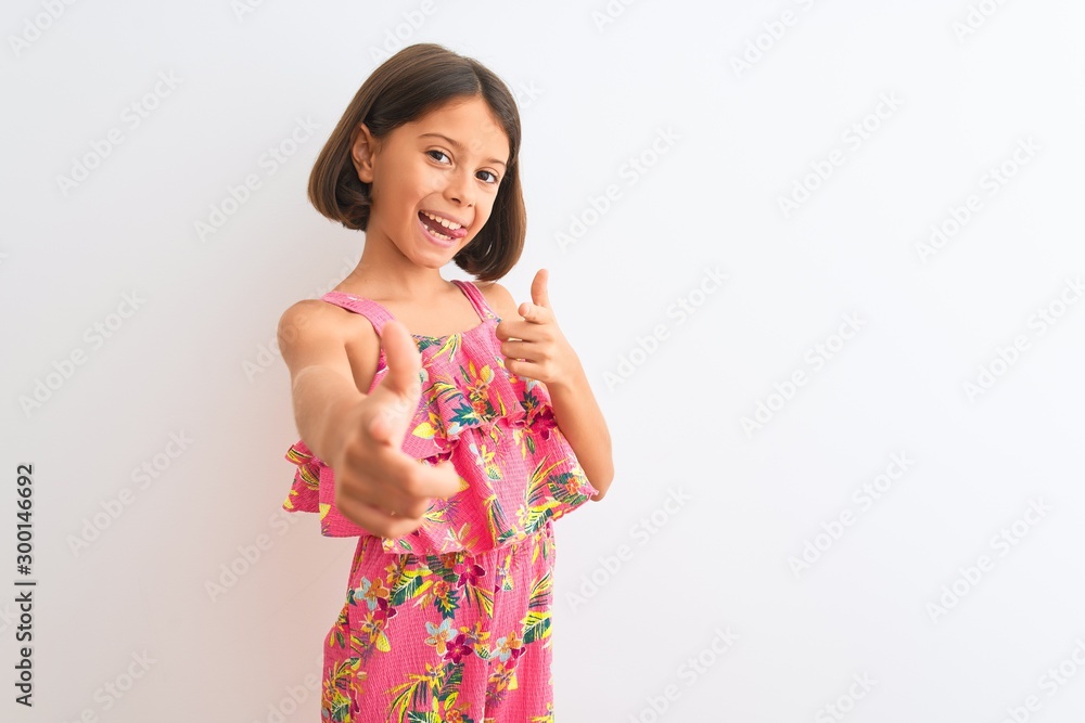 Young beautiful child girl wearing pink floral dress standing over isolated white background pointing fingers to camera with happy and funny face. Good energy and vibes. Young beautiful child girl wearing pink floral dress standing over isolated white background pointing fingers to camera with happy and funny face. Good energy and vibes.