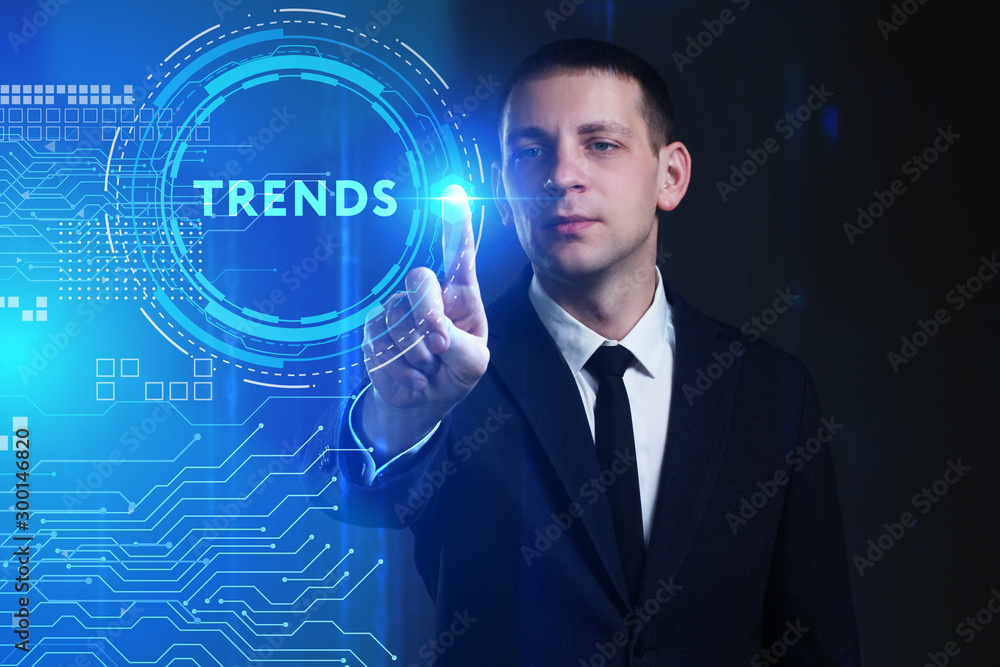 Business, Technology, Internet and network concept. Young businessman working on a virtual screen of the future and sees the inscription: Trends Business, Technology, Internet and network concept. Young businessman working on a virtual screen of the future and sees the inscription: Trends