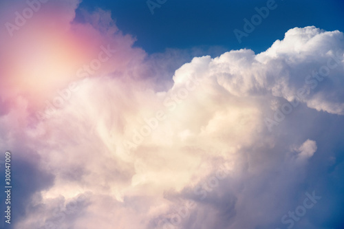 detail of white clouds and blue sky in orange sunset light.