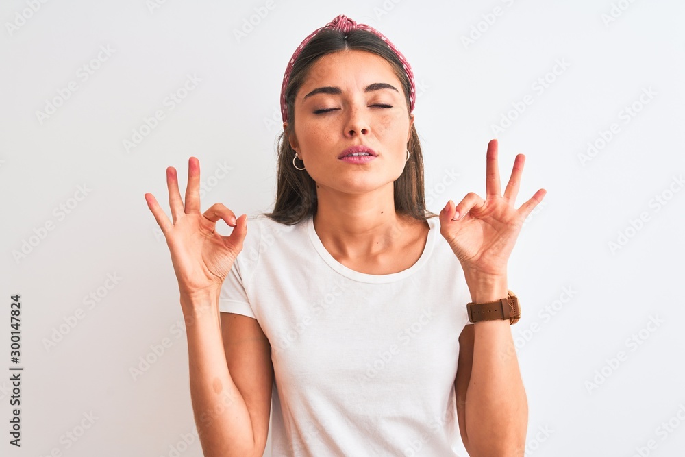 Young beautiful woman wearing casual t-shirt and diadem over isolated white background relax and smiling with eyes closed doing meditation gesture with fingers. Yoga concept. Young beautiful woman wearing casual t-shirt and diadem over isolated white background relax and smiling with eyes closed doing meditation gesture with fingers. Yoga concept.