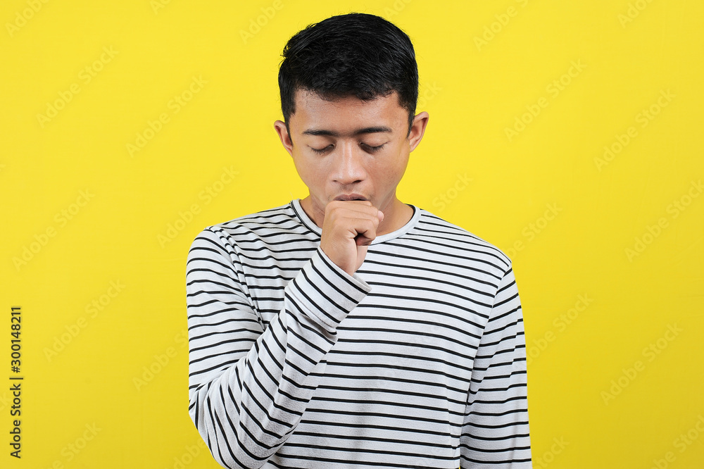 Portrait of funny Asian man yawning covering open mouth and showing a sleepy gesture. feeling being tired from hard work, isolated on yellow Portrait of funny Asian man yawning covering open mouth and showing a sleepy gesture. feeling being tired from hard work, isolated on yellow