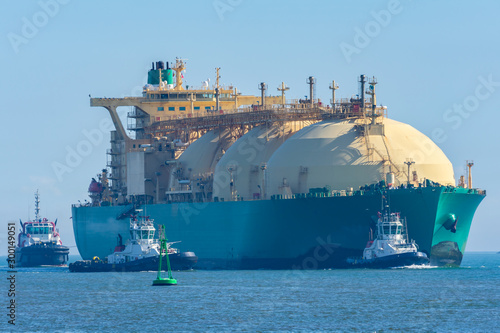 Barco mercante para el transporte de gas entrando a puerto acompañado de remolcadorescarga photo