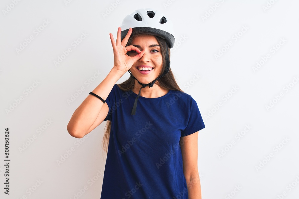 Young beautiful cyclist woman wearing security bike helmet over isolated white background doing ok gesture with hand smiling, eye looking through fingers with happy face. Young beautiful cyclist woman wearing security bike helmet over isolated white background doing ok gesture with hand smiling, eye looking through fingers with happy face.