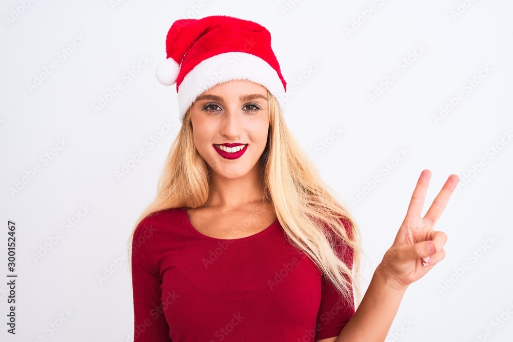 Young beautiful woman wearing Christmas Santa hat over isolated white background showing and pointing up with fingers number two while smiling confident and happy. Young beautiful woman wearing Christmas Santa hat over isolated white background showing and pointing up with fingers number two while smiling confident and happy.