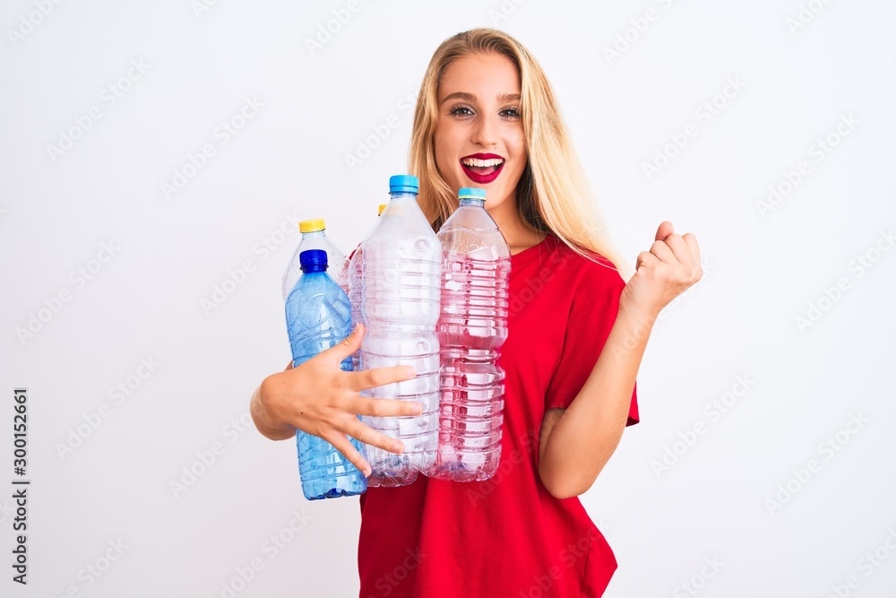 Young beautiful woman recycling plastic bottles standing over isolated white background screaming proud and celebrating victory and success very excited, cheering emotion Young beautiful woman recycling plastic bottles standing over isolated white background screaming proud and celebrating victory and success very excited, cheering emotion