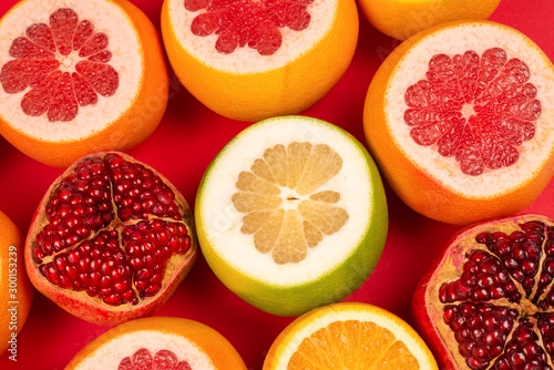 Grapefruit  orange  pomegranate  citrus sweetie on red background.