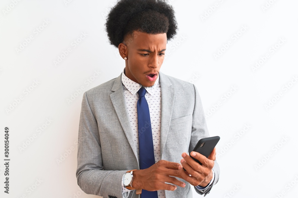 Young african american businessman using smartphone over isolated white background scared in shock with a surprise face, afraid and excited with fear expression Young african american businessman using smartphone over isolated white background scared in shock with a surprise face, afraid and excited with fear expression