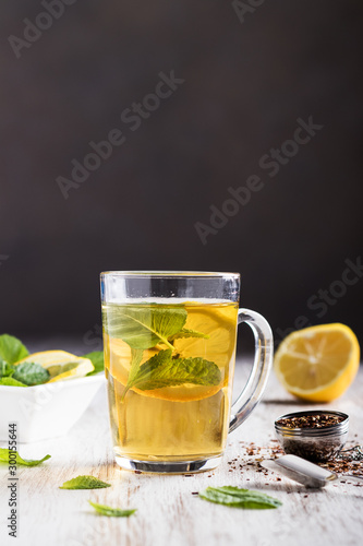 cup of tea with cut lemon and mint on a white wooden board