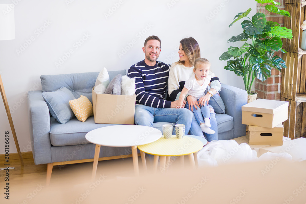 Beautiful family with kid sitting on the sofa drinking coffee at new home around cardboard boxes Beautiful family with kid sitting on the sofa drinking coffee at new home around cardboard boxes
