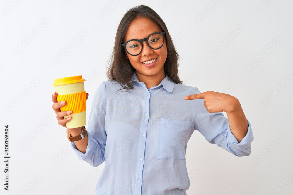 Young chinese woman wearing glasses holding glass of coffee over isolated white background with surprise face pointing finger to himself Young chinese woman wearing glasses holding glass of coffee over isolated white background with surprise face pointing finger to himself