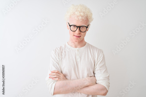 Obraz na plátne Young albino blond man wearing t-shirt and glasses standing over isolated white background skeptic and nervous, disapproving expression on face with crossed arms
