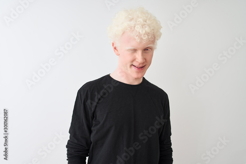 Young albino blond man wearing black t-shirt standing over isolated white background winking looking at the camera with sexy expression, cheerful and happy face.