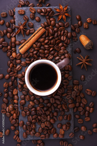 Beautiful composition of coffee beans, utensils for making coffee and decor in the form of almonds, dried slices of lemon, peanut and cinnamon on black and blue backgrounds.