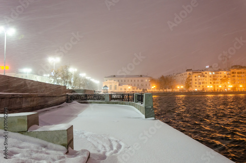River embankment at night in winter in a snowstorm.