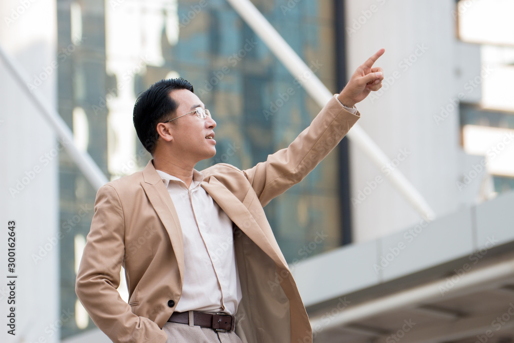 Asian businessman pointing at something and looking at it Asian businessman pointing at something and looking at it