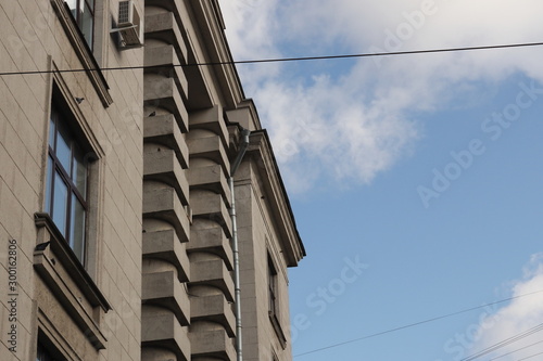 Urban look at the sky - gray house facade and blue sky with clouds