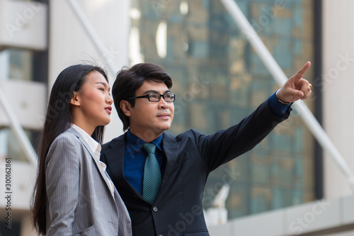 Asian businessman pointing at something and looking at it