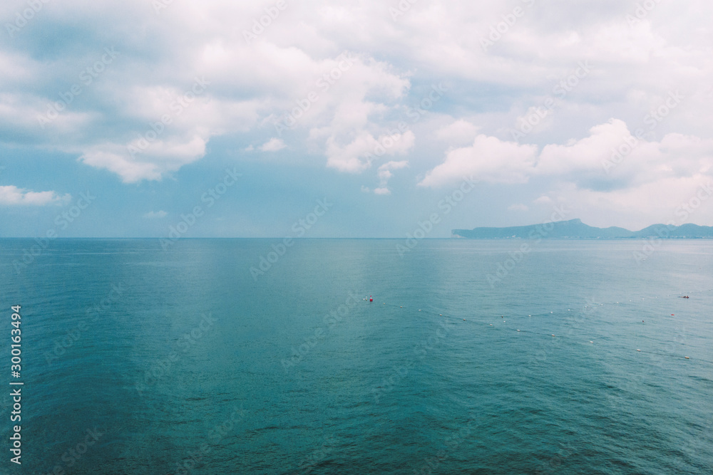 Obraz premium Beautiful ocean panorama. Scenic seascape. Azure water landscape with blue sky, horizon and white fluffy clouds. Sea turquoise surface. Summer vacation. Wild nature paradise background