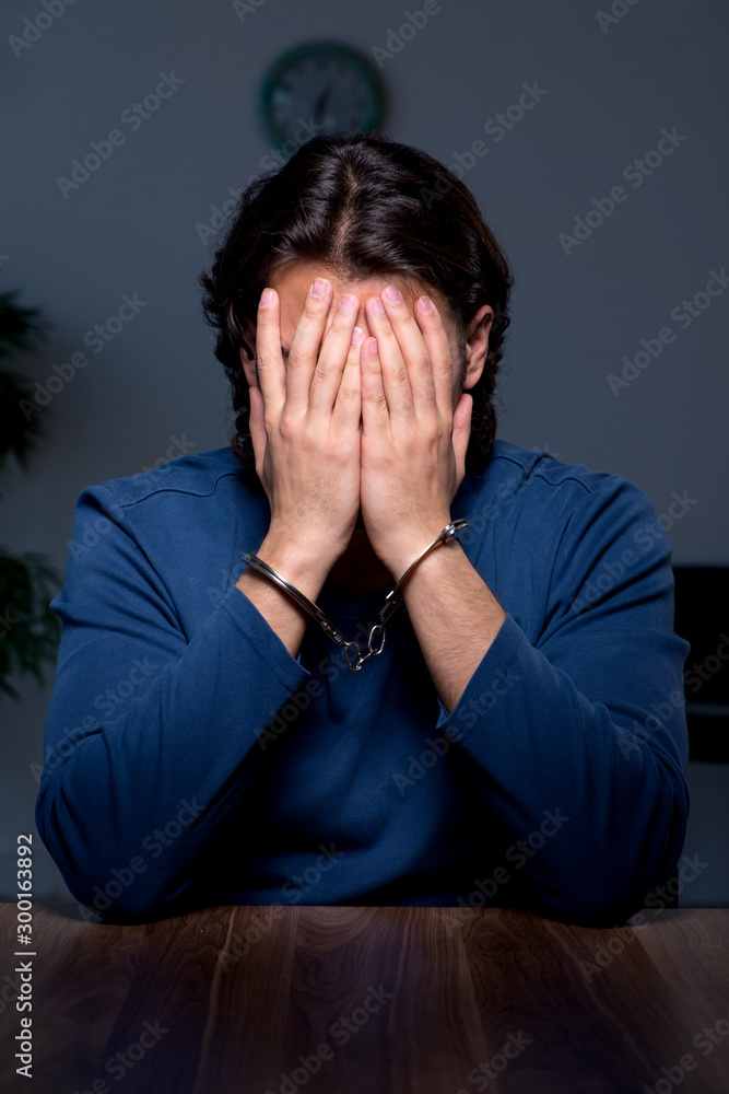 Young convict man sitting in dark room Young convict man sitting in dark room