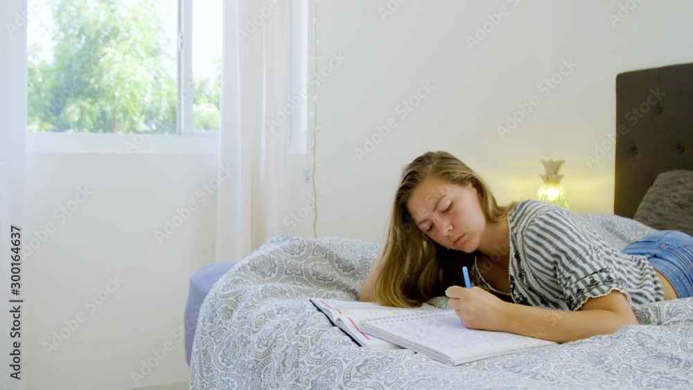 Girl studying for university while doing homework laying on bed Girl studying for university while doing homework laying on bed