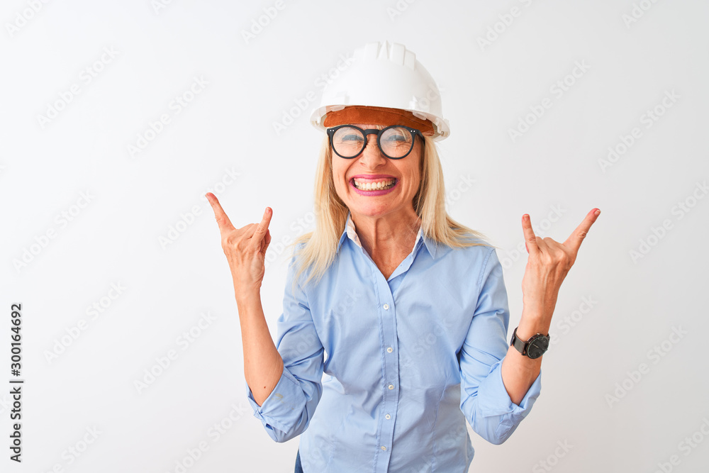 Middle age architect woman wearing glasses and helmet over isolated white background shouting with crazy expression doing rock symbol with hands up. Music star. Heavy concept.