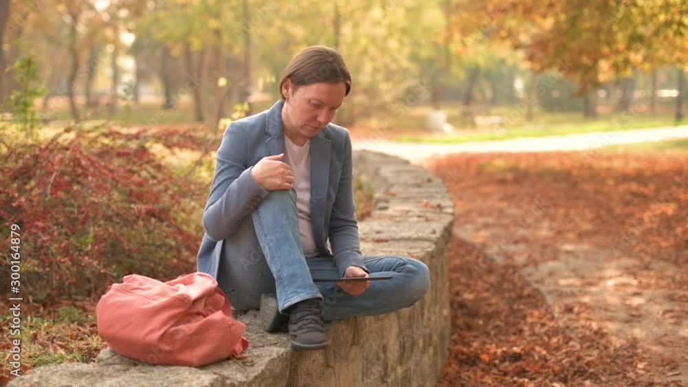 Businesswoman using digital tablet in autumnal park Businesswoman using digital tablet in autumnal park