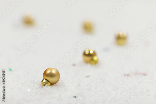 Golden Christmas balls laying in the snow on a table, template for postcard with space for text