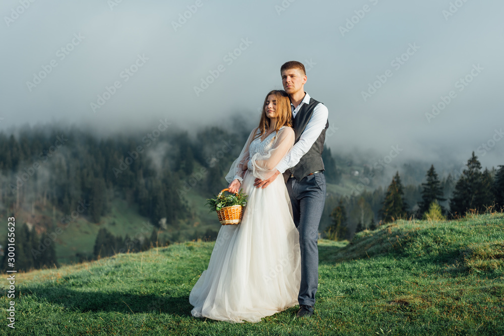 Beautiful wedding couple posing upon hills on fog