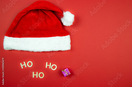 Czapka świętego Mikołaja na czerwonym tle z prezentem i napisem Ho Ho Ho