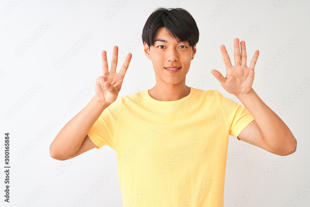 Chinese man wearing yellow casual t-shirt standing over isolated white background showing and pointing up with fingers number eight while smiling confident and happy. Chinese man wearing yellow casual t-shirt standing over isolated white background showing and pointing up with fingers number eight while smiling confident and happy.