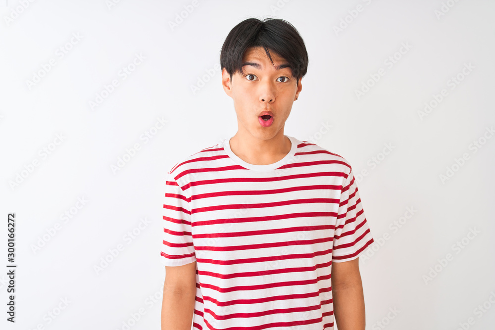 Young chinese man wearing casual striped t-shirt standing over isolated white background afraid and shocked with surprise expression, fear and excited face. Young chinese man wearing casual striped t-shirt standing over isolated white background afraid and shocked with surprise expression, fear and excited face.
