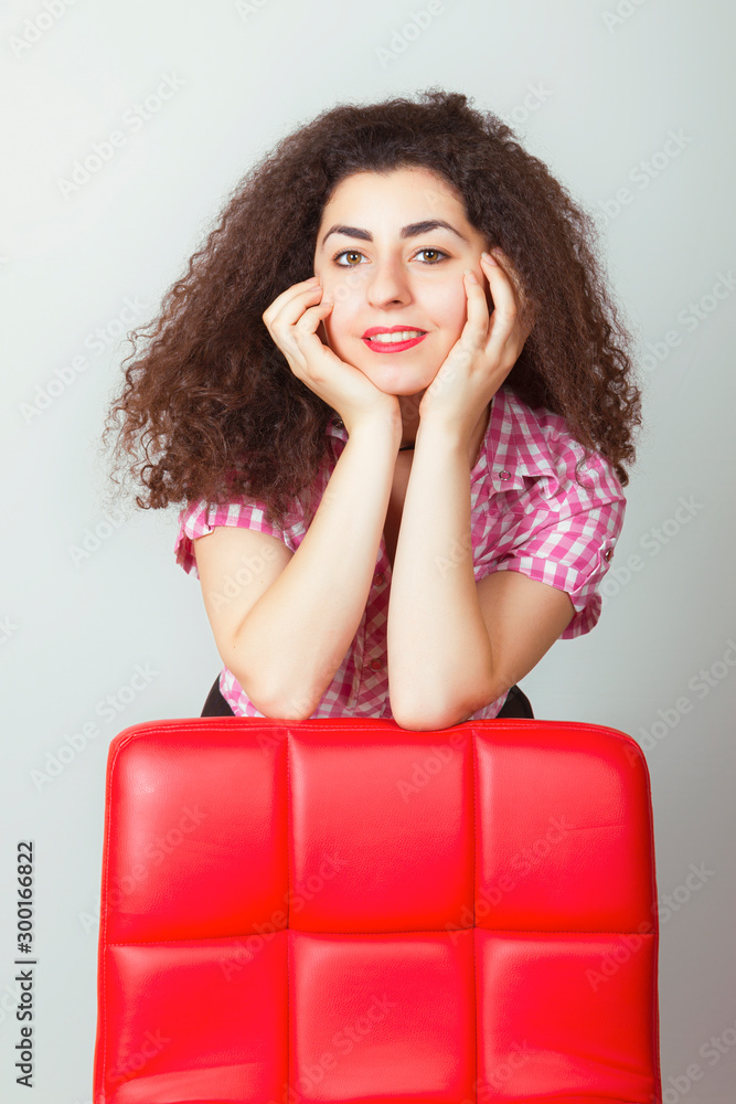 Girl with curly magnificent hair rested her elbows on a chair. Girl with curly magnificent hair rested her elbows on a chair.
