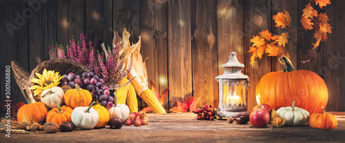 Pumpkins with fruits and falling leaves on rustic wooden table photo