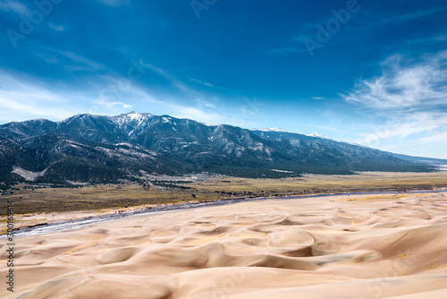 Sand dunes and mountains separated by a river.