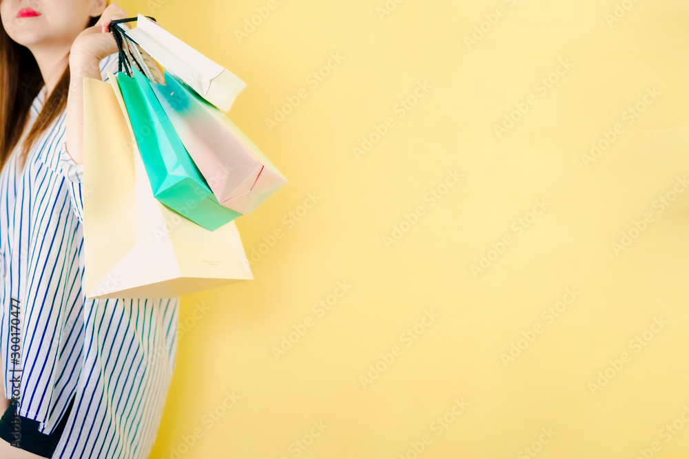 mid season sale and shopping activity from asian beauty 30s to 40s hold the shopping bag with happiness feeling with copy space and yellow vintage background
