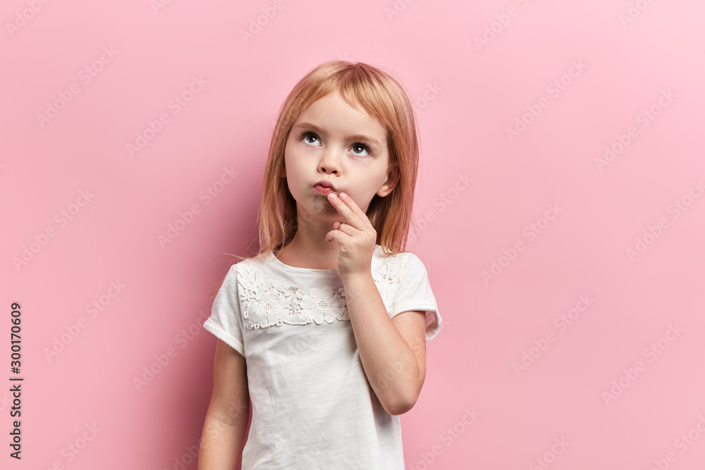 serious pensive girl with a finger on her chin looking up, close up photo. isolated pink background, idea, plan , faciala expression, reaction - obrazy, fototapety, plakaty 