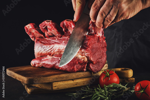 Male butcher cuts raw beef meat.